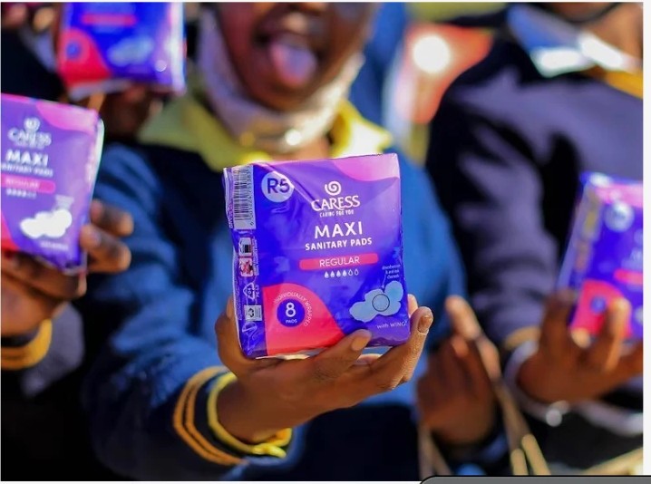 Schoolgirls holding packs of sanitary pads received from a Phehello girl supplies drive